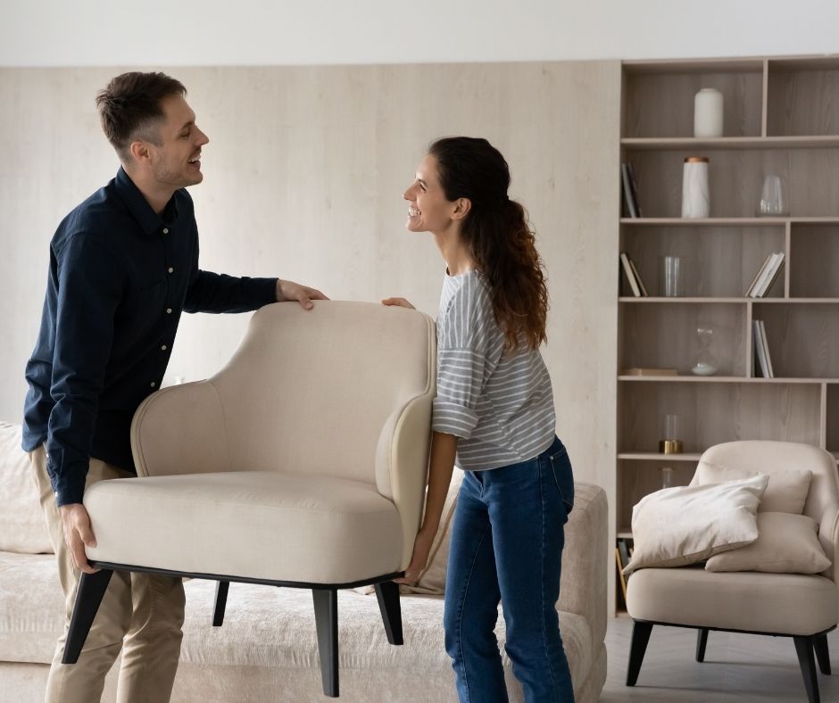 man and woman moving an armchair in their home